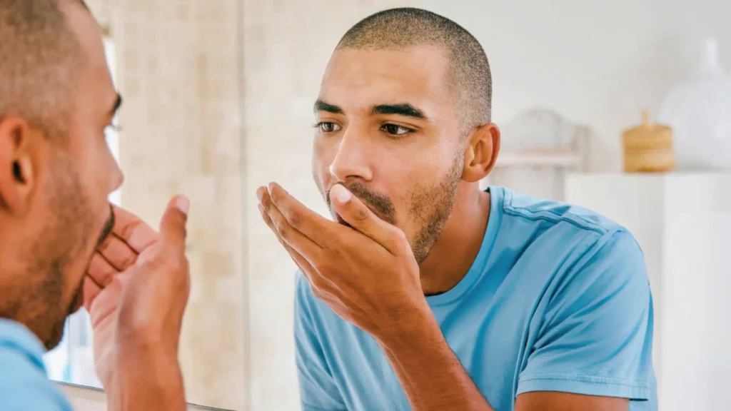 Man smelling own bad breath